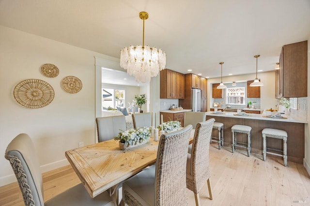 dining space featuring baseboards, light wood-type flooring, an inviting chandelier, and recessed lighting