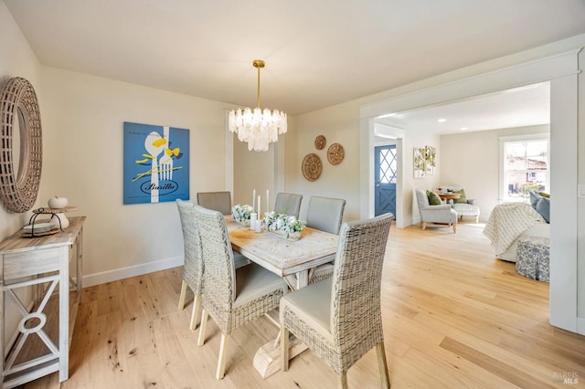 dining space featuring light wood finished floors, baseboards, and an inviting chandelier