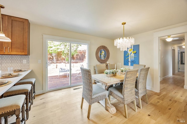 dining space with baseboards, light wood finished floors, a notable chandelier, and visible vents