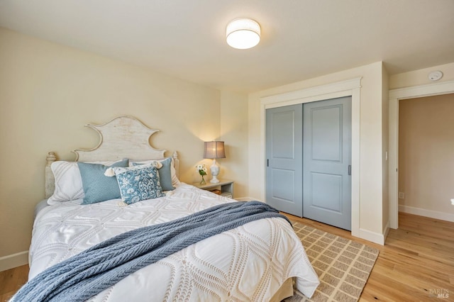 bedroom with a closet, baseboards, and light wood finished floors