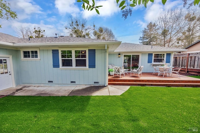 back of property featuring a shingled roof, a deck, a fenced backyard, and a lawn