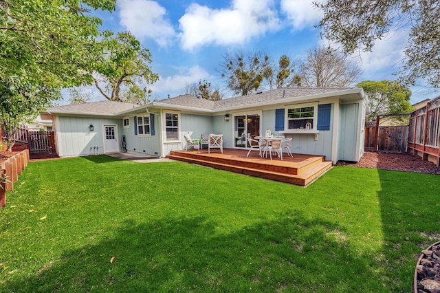 rear view of house featuring a fenced backyard, a deck, a lawn, and roof with shingles