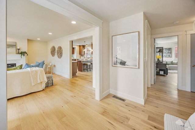interior space with light wood-style floors, a fireplace, visible vents, recessed lighting, and baseboards
