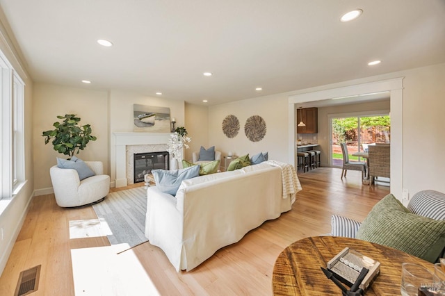 living area featuring a high end fireplace, light wood-type flooring, visible vents, recessed lighting, and baseboards