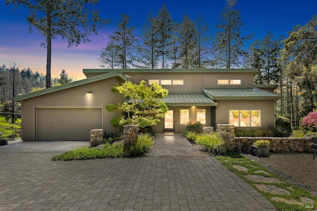 mid-century modern home featuring a garage, stucco siding, and decorative driveway