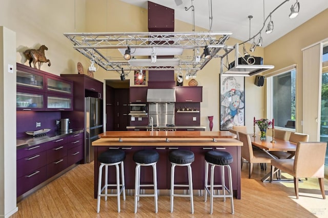 kitchen with butcher block countertops, appliances with stainless steel finishes, modern cabinets, and light wood-style flooring