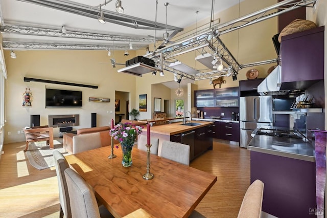 dining room featuring a lit fireplace, a high ceiling, and wood finished floors