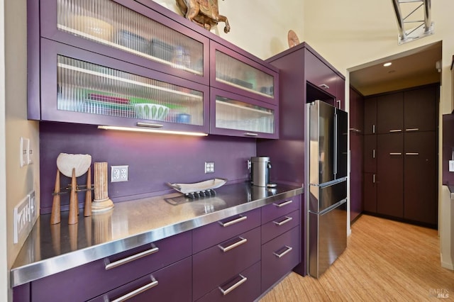 kitchen with light wood-type flooring, high end refrigerator, stainless steel counters, and modern cabinets