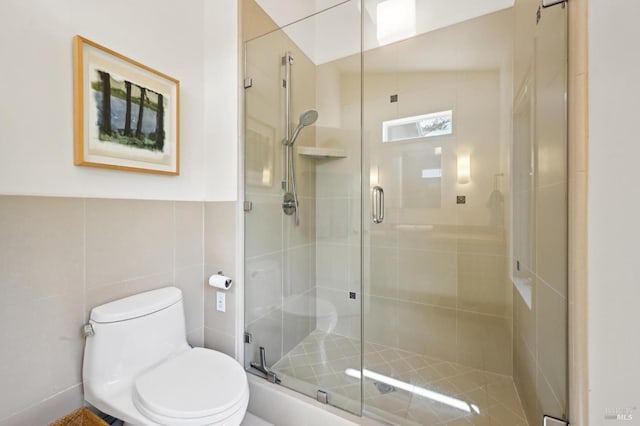 bathroom with toilet, tile walls, and a stall shower