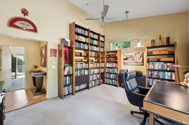 carpeted office featuring a high ceiling and ceiling fan