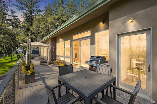 deck at dusk featuring outdoor dining space and a grill