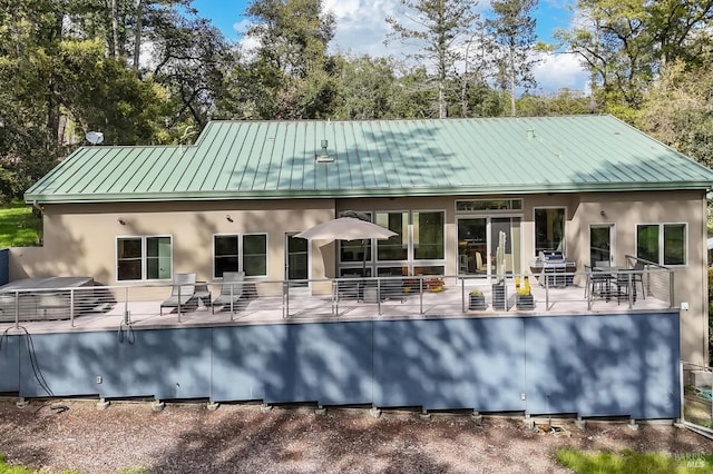 rear view of property featuring a patio, metal roof, stucco siding, and a standing seam roof
