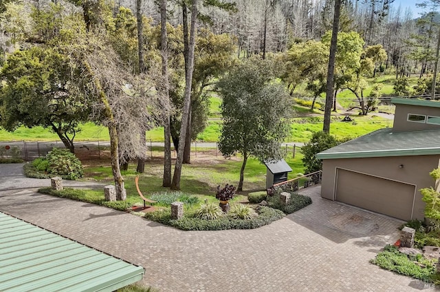 exterior space featuring decorative driveway, a yard, fence, and an attached garage