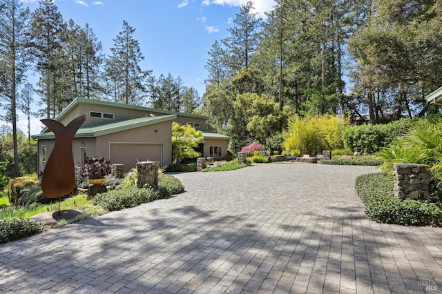 view of side of home featuring a garage, stucco siding, and decorative driveway