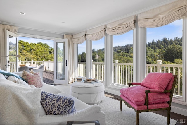 sunroom / solarium featuring crown molding, wood finished floors, and a deck