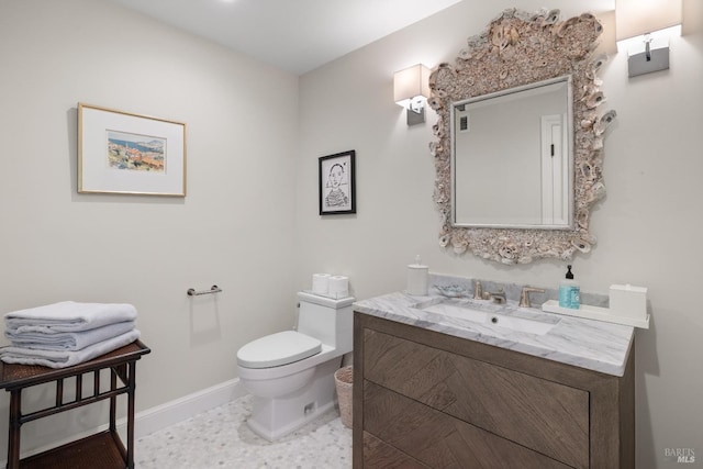half bathroom featuring toilet, baseboards, and vanity