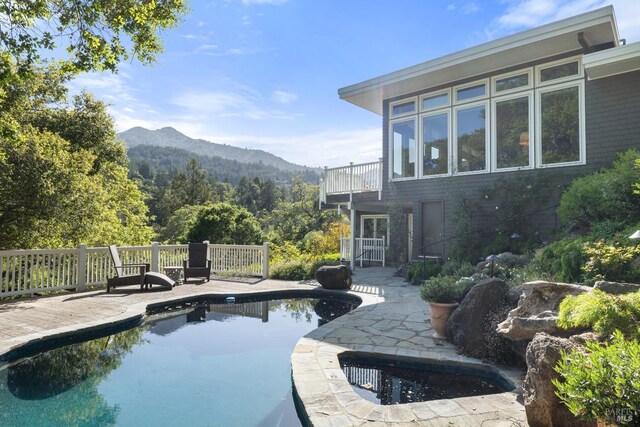 view of swimming pool with a forest view, a fenced in pool, a mountain view, and a patio area