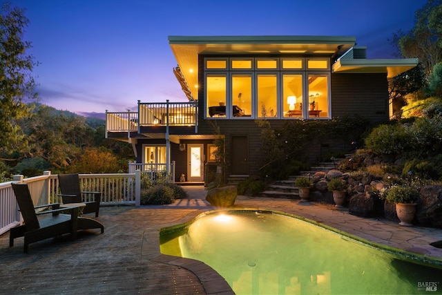 back of house with an outdoor pool and a balcony