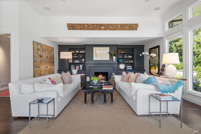 living room with plenty of natural light, ornamental molding, and a lit fireplace