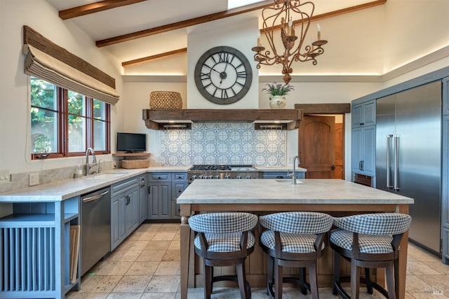 kitchen with tasteful backsplash, gray cabinetry, beam ceiling, stainless steel appliances, and a sink