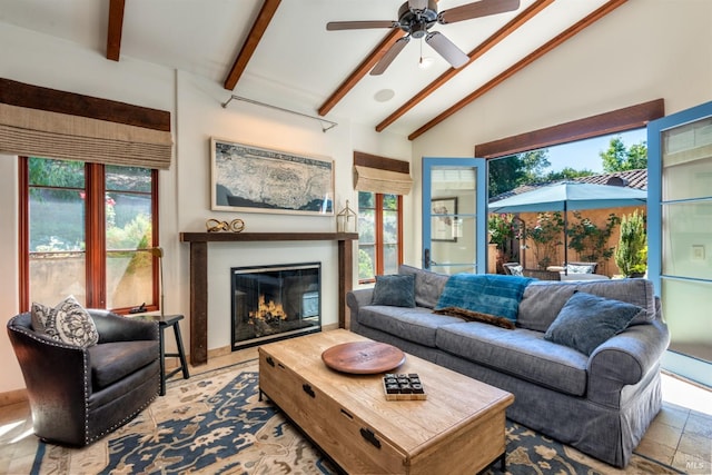 living area featuring a glass covered fireplace, plenty of natural light, ceiling fan, and lofted ceiling with beams