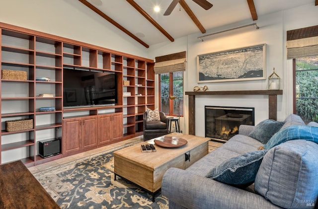 living room featuring a glass covered fireplace, a ceiling fan, and lofted ceiling with beams