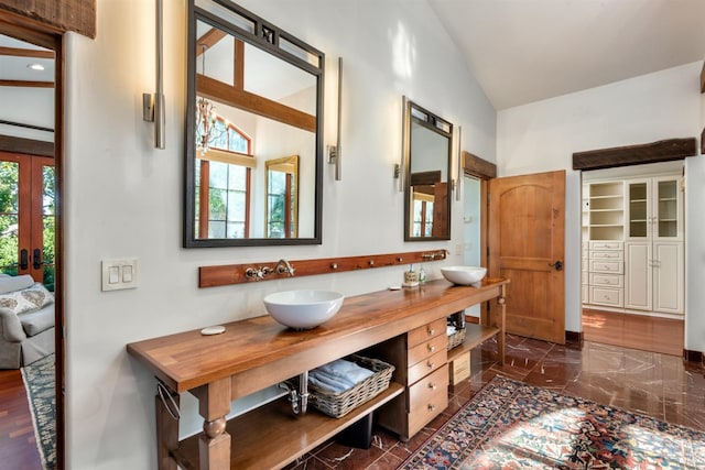 bathroom with double vanity, a sink, vaulted ceiling, and a wealth of natural light