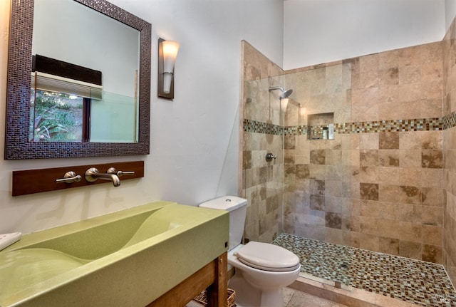 full bathroom with a tile shower, tile patterned flooring, toilet, and vanity