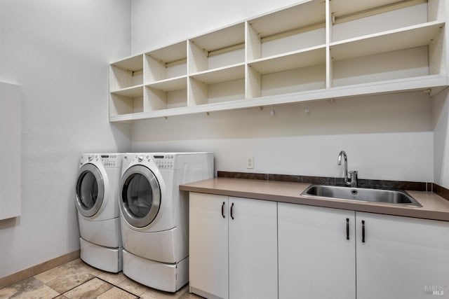 laundry area featuring a sink, washing machine and clothes dryer, cabinet space, and baseboards