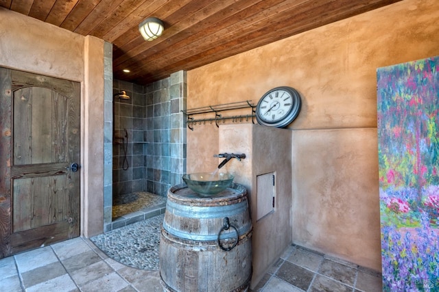bathroom featuring tiled shower, stone tile floors, and wood ceiling