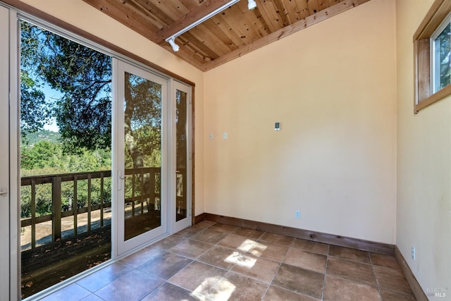 spare room featuring wood ceiling, beamed ceiling, baseboards, and plenty of natural light
