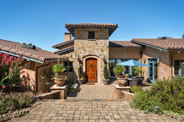 view of front of home with a tiled roof, stone siding, and stucco siding