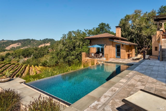 view of swimming pool with an infinity pool and a patio