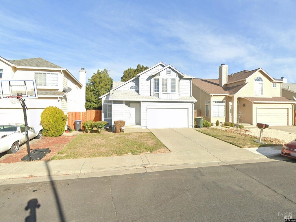 view of front of property with concrete driveway, an attached garage, fence, and a front lawn