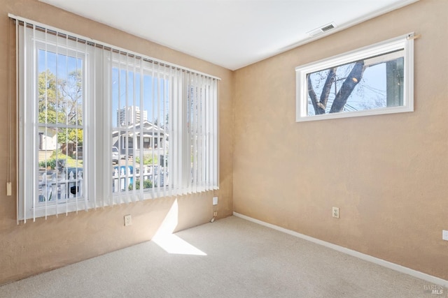 unfurnished room with carpet flooring, visible vents, and baseboards