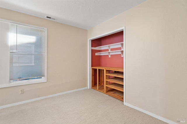 unfurnished bedroom with visible vents, baseboards, carpet flooring, and a textured ceiling