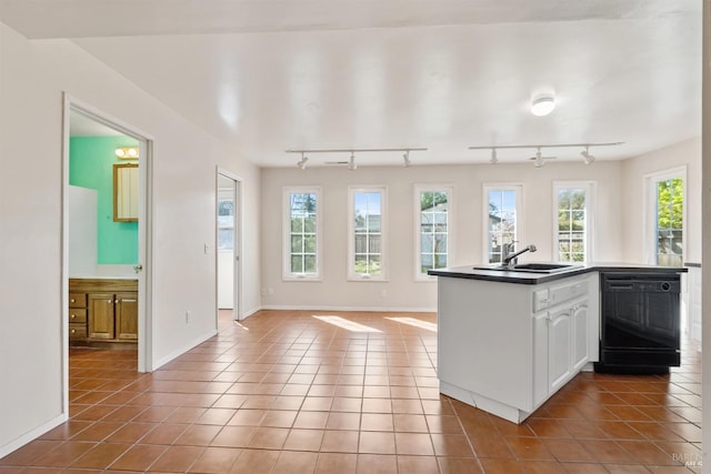 kitchen featuring light tile patterned flooring, dishwasher, a sink, dark countertops, and open floor plan