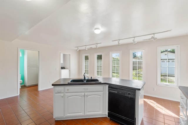 kitchen featuring a sink, washer and clothes dryer, dark countertops, and dishwasher