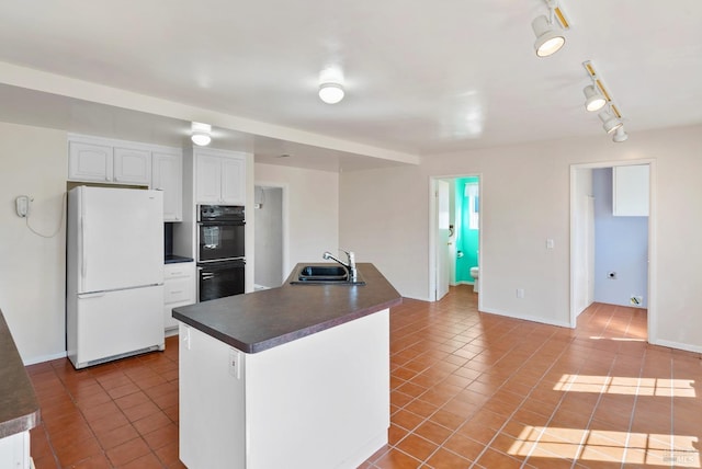 kitchen with a sink, freestanding refrigerator, dark countertops, white cabinetry, and tile patterned floors