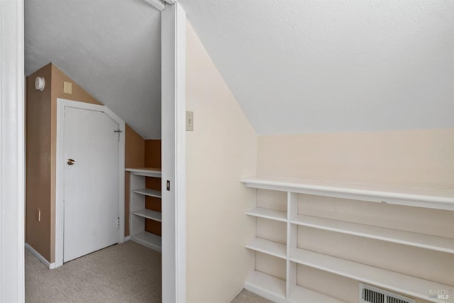 walk in closet featuring visible vents, carpet, and lofted ceiling