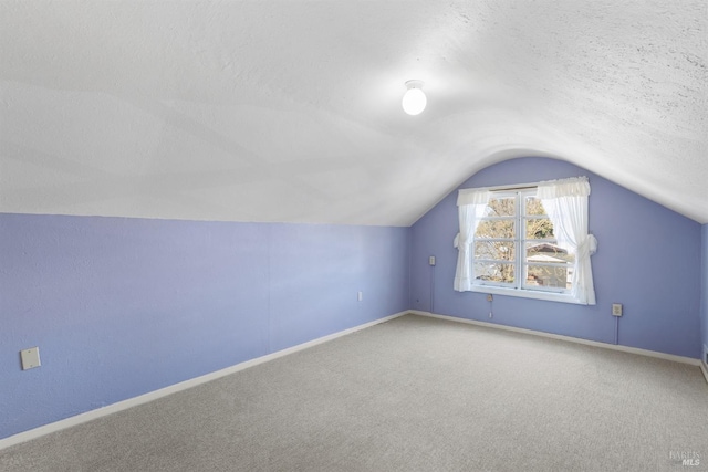 additional living space with a textured ceiling, baseboards, carpet, and vaulted ceiling