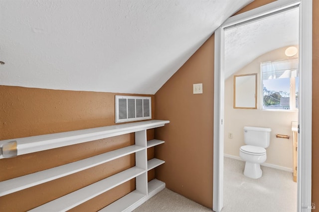 bathroom featuring a textured ceiling, vaulted ceiling, visible vents, toilet, and baseboards