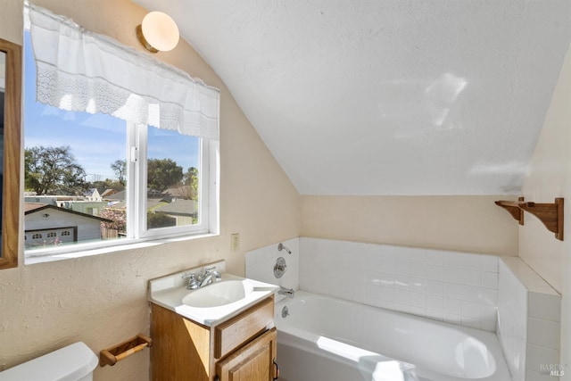 full bathroom featuring toilet, a bath, vanity, and lofted ceiling