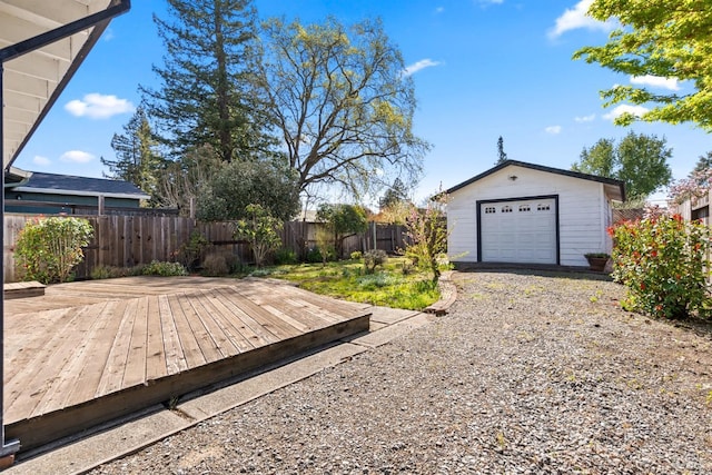 view of yard featuring a wooden deck, an outdoor structure, fence, and a detached garage