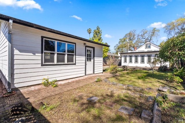 back of property with a yard, fence, and an outbuilding