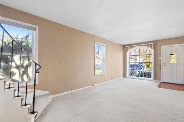 carpeted entrance foyer with stairs and baseboards