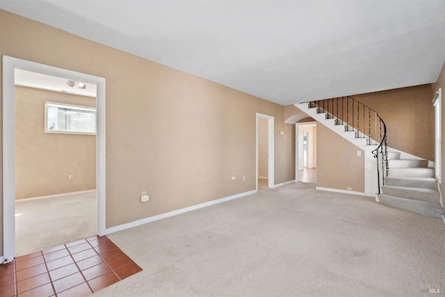 unfurnished living room with baseboards, arched walkways, stairs, tile patterned floors, and carpet flooring