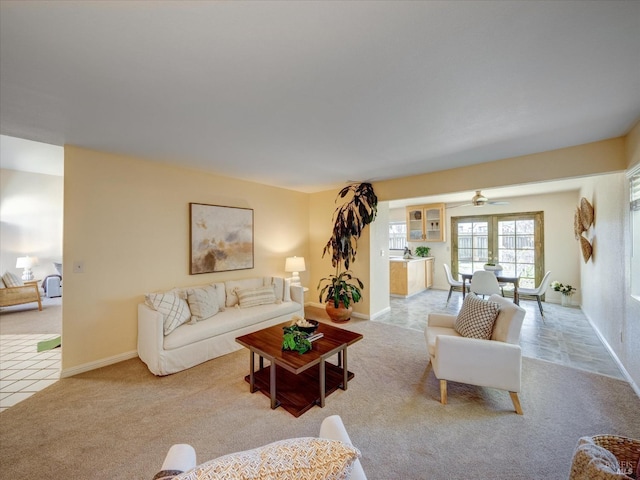 carpeted living area featuring baseboards and a ceiling fan