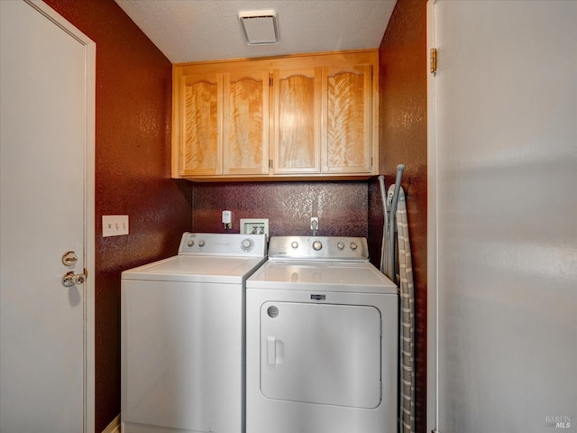 laundry room with cabinet space, separate washer and dryer, and a textured wall