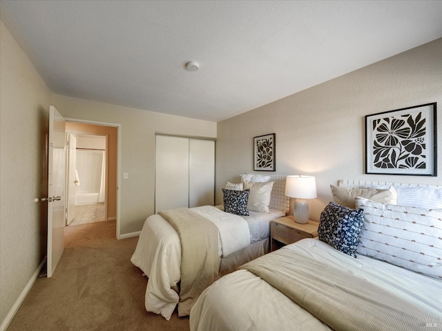 carpeted bedroom featuring a closet and baseboards